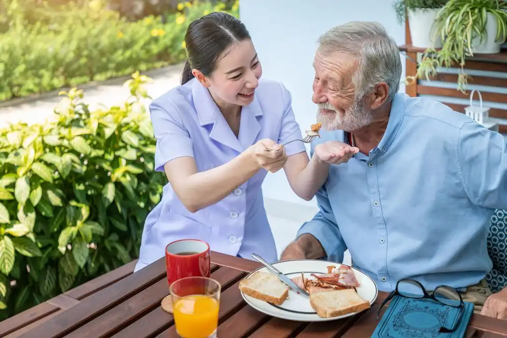 Nurse helping an elderly with eating outdoors